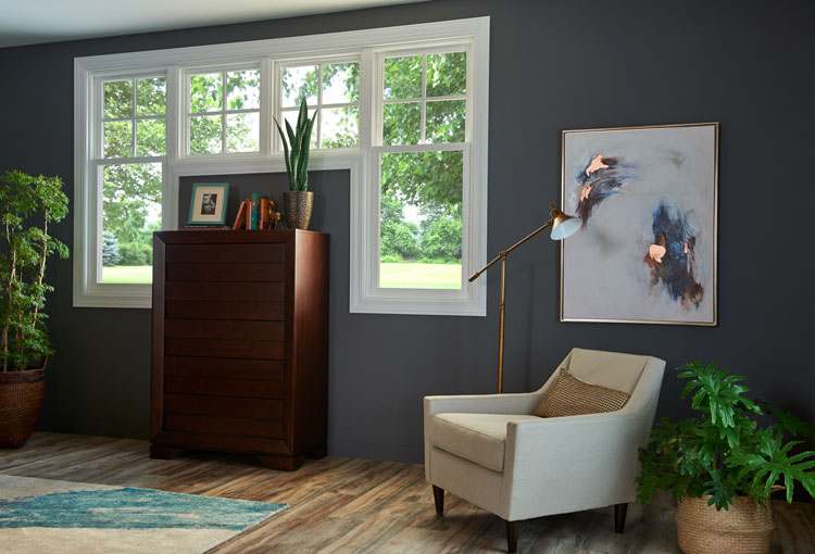 double-hung-windows-above-a-dresser-in-a-blue-painted-room-with-pictures-and-white-chair